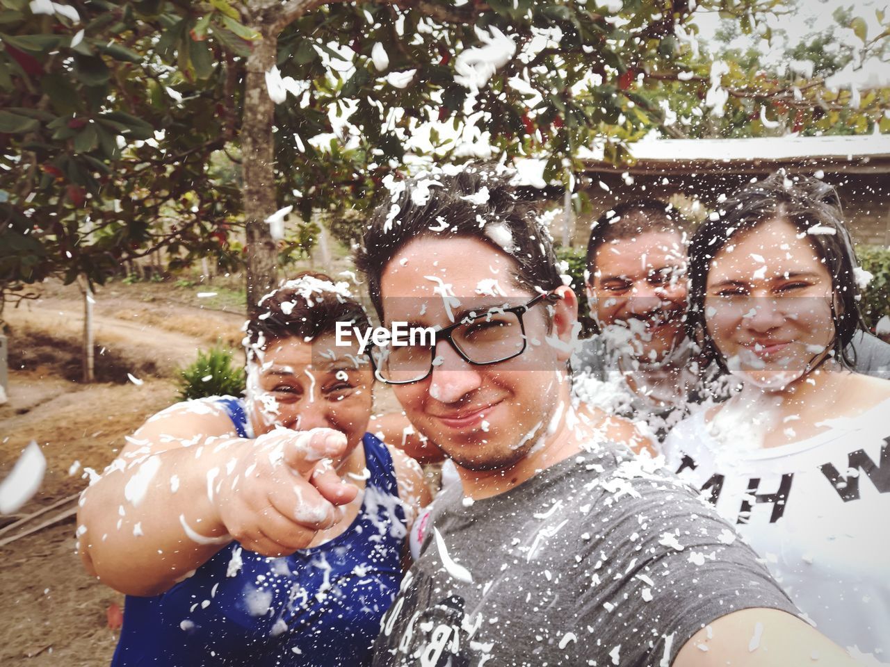 Portrait of smiling friends with party spray standing outdoors