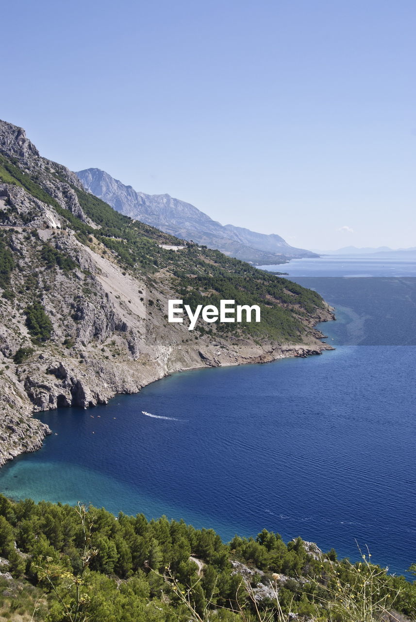 Scenic view of sea and mountains against clear sky