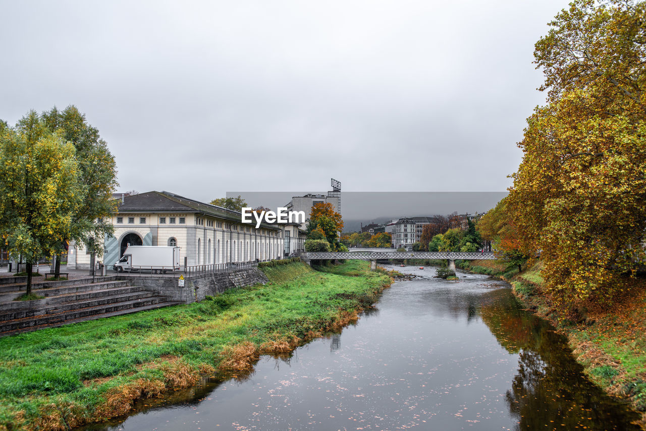 RIVER BY BUILDINGS AGAINST SKY