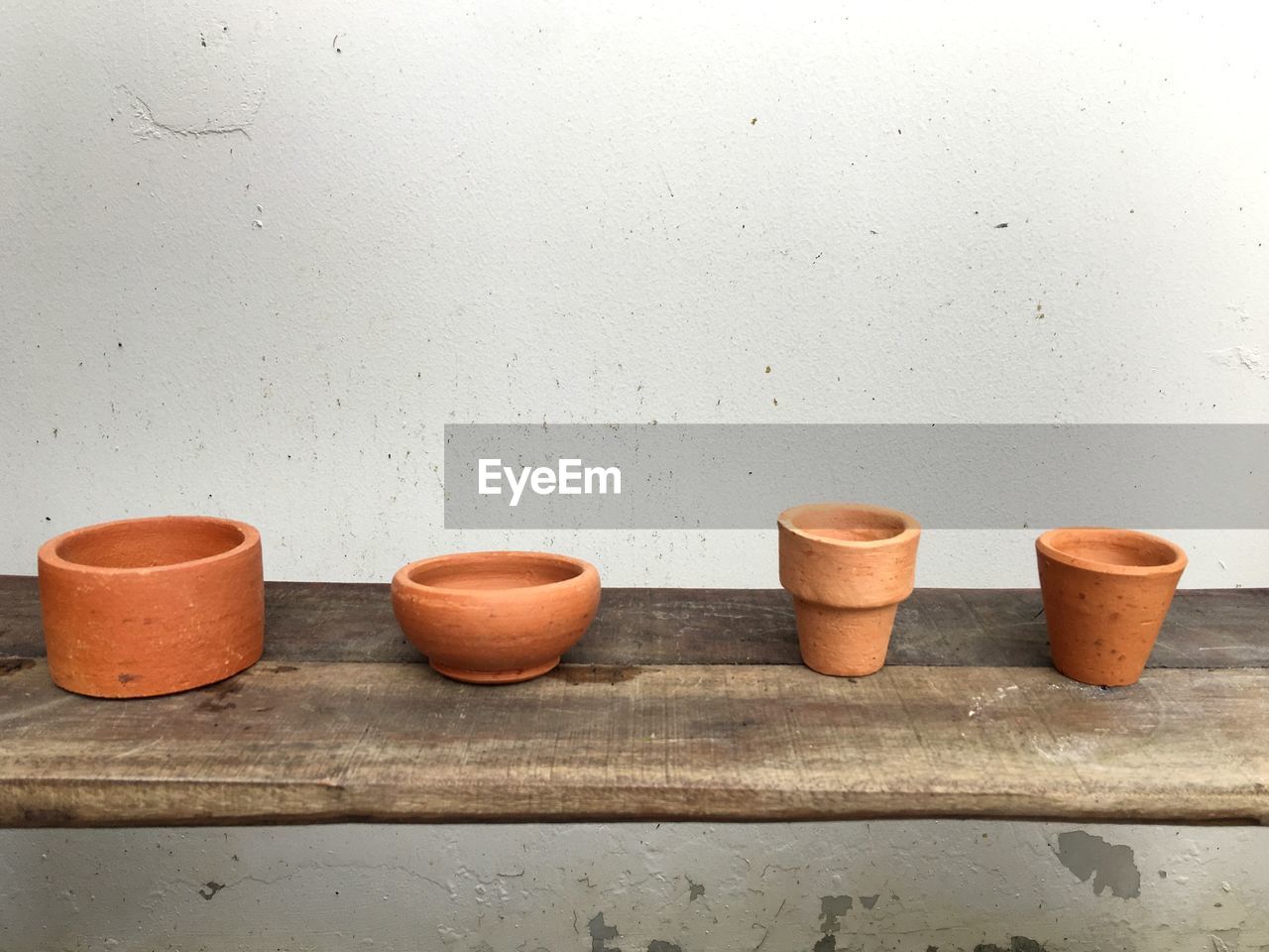High angle view of various pots on wooden table by wall