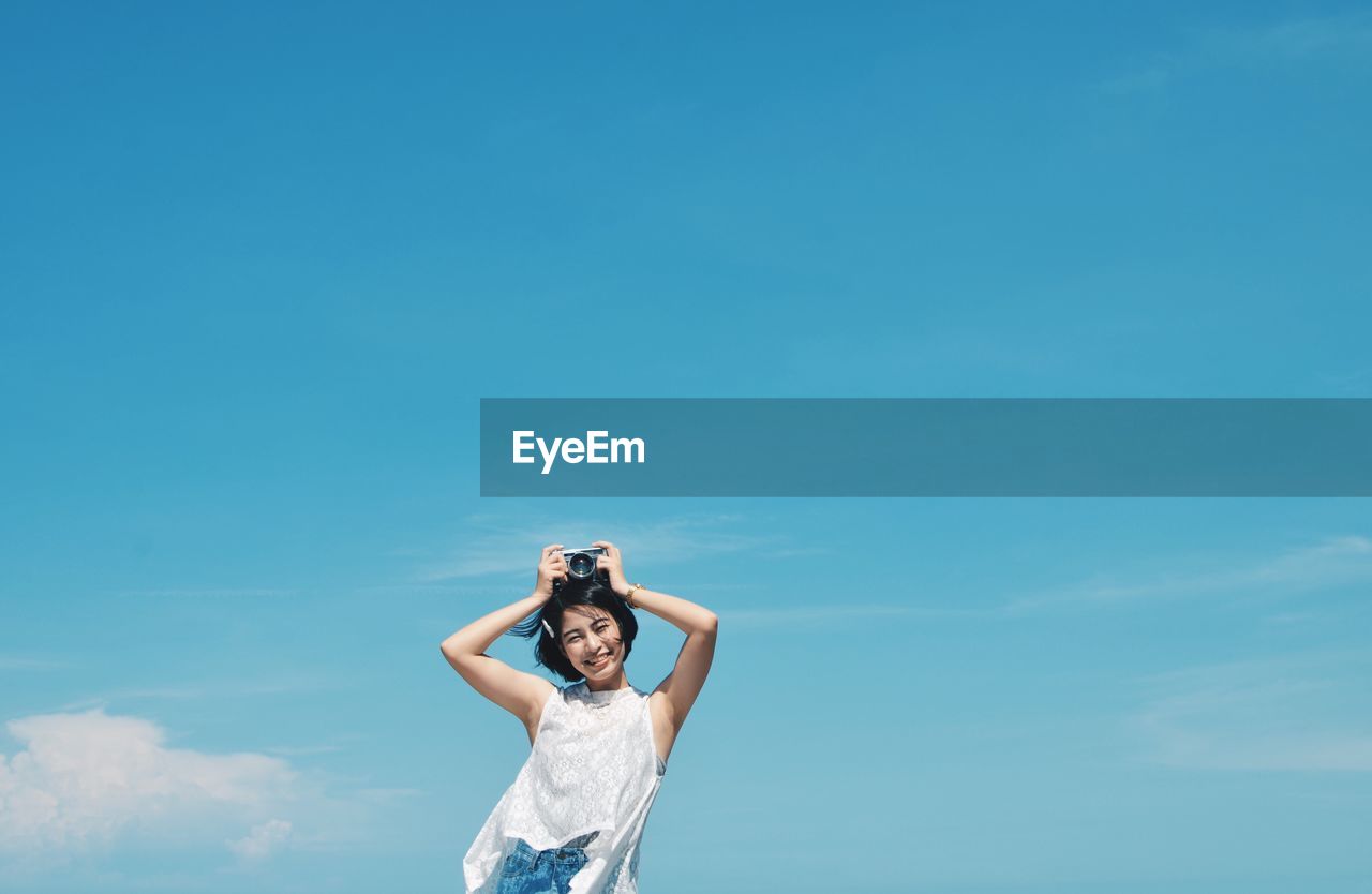 Low angle view of woman standing against blue sky