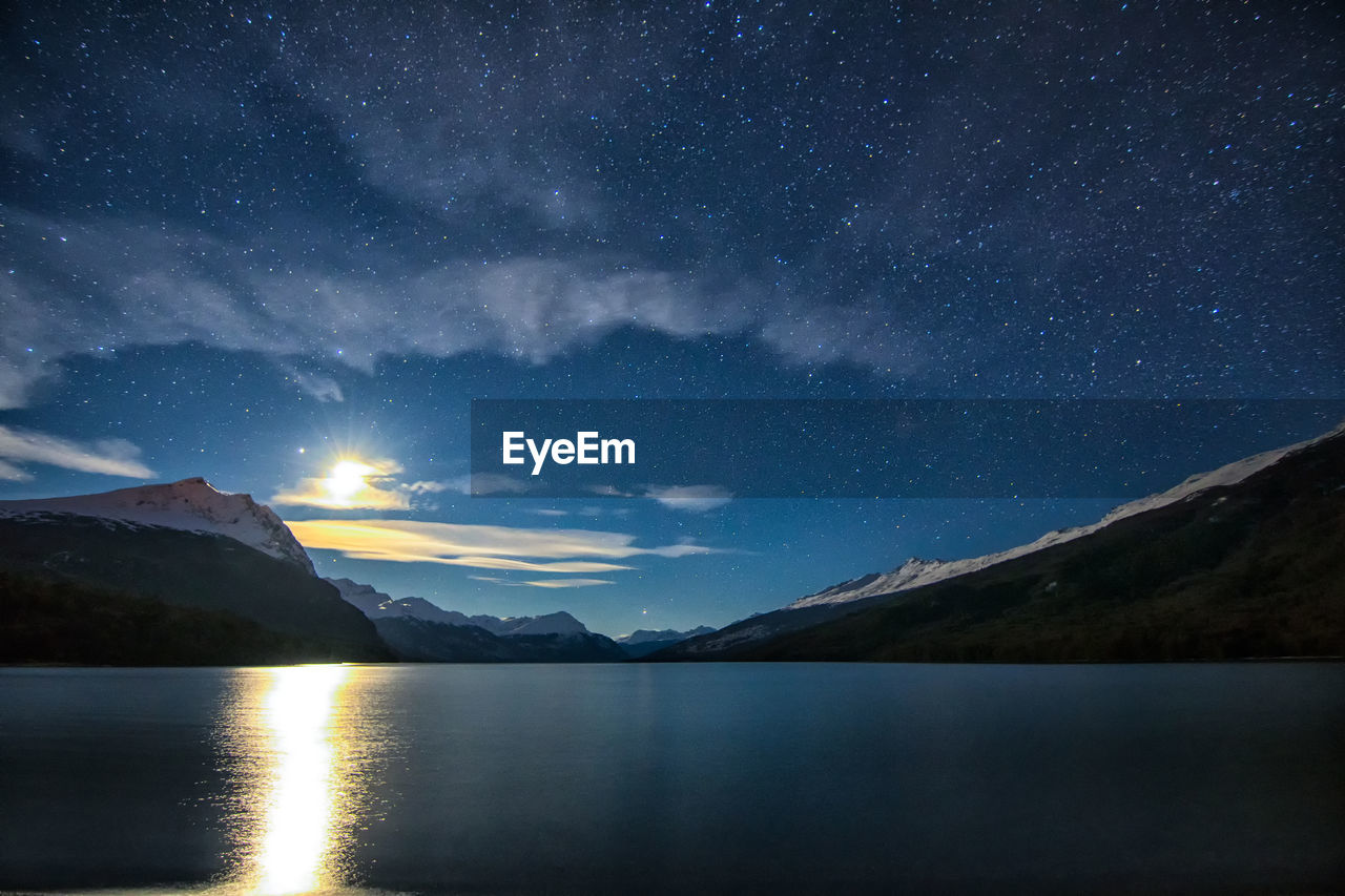 Scenic view of lake and mountains against sky at night