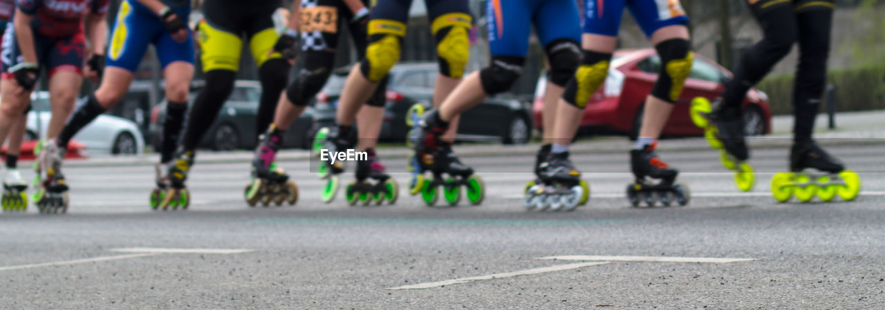 Low section of people inline skating on road