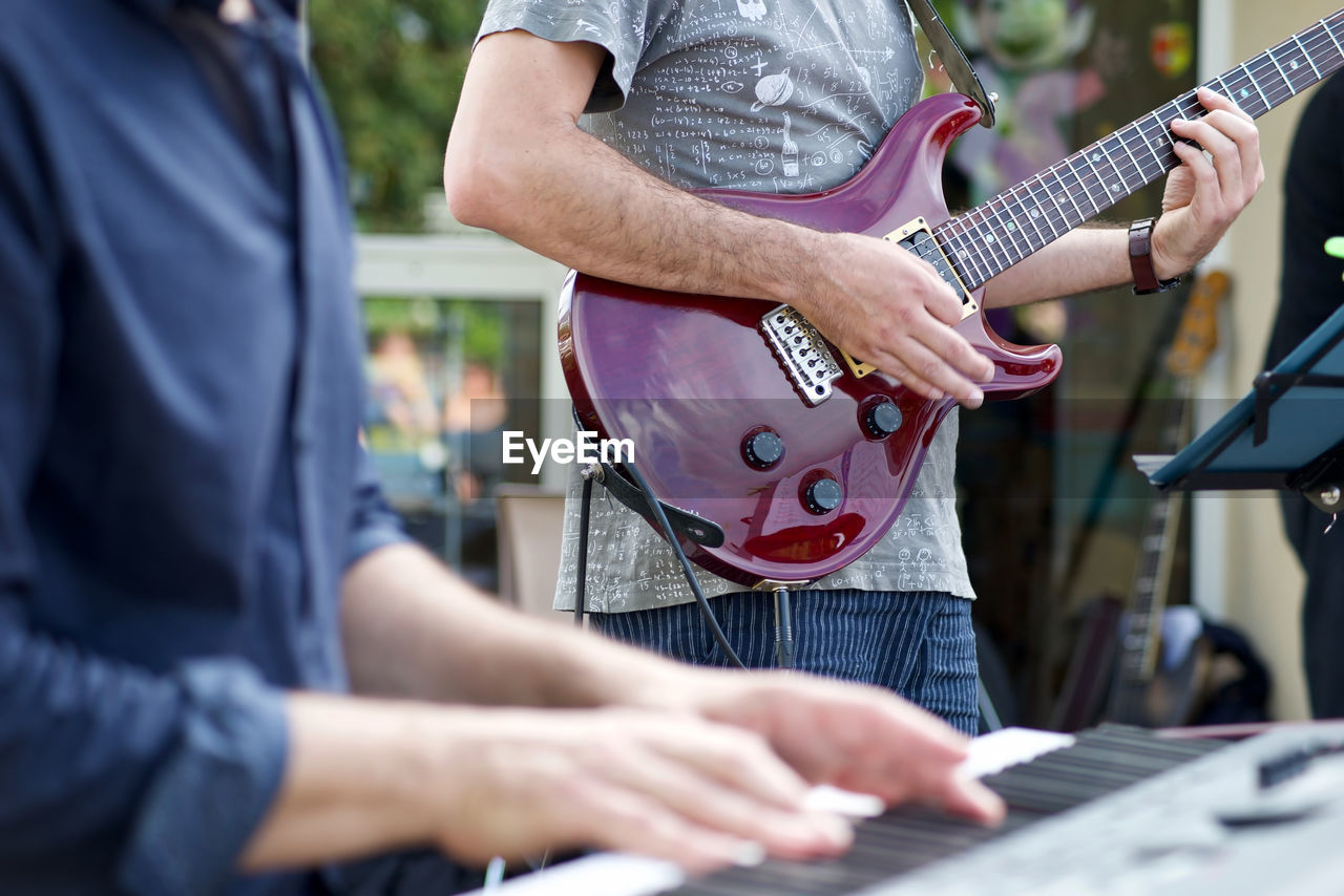 Midsection of man playing guitar outdoors