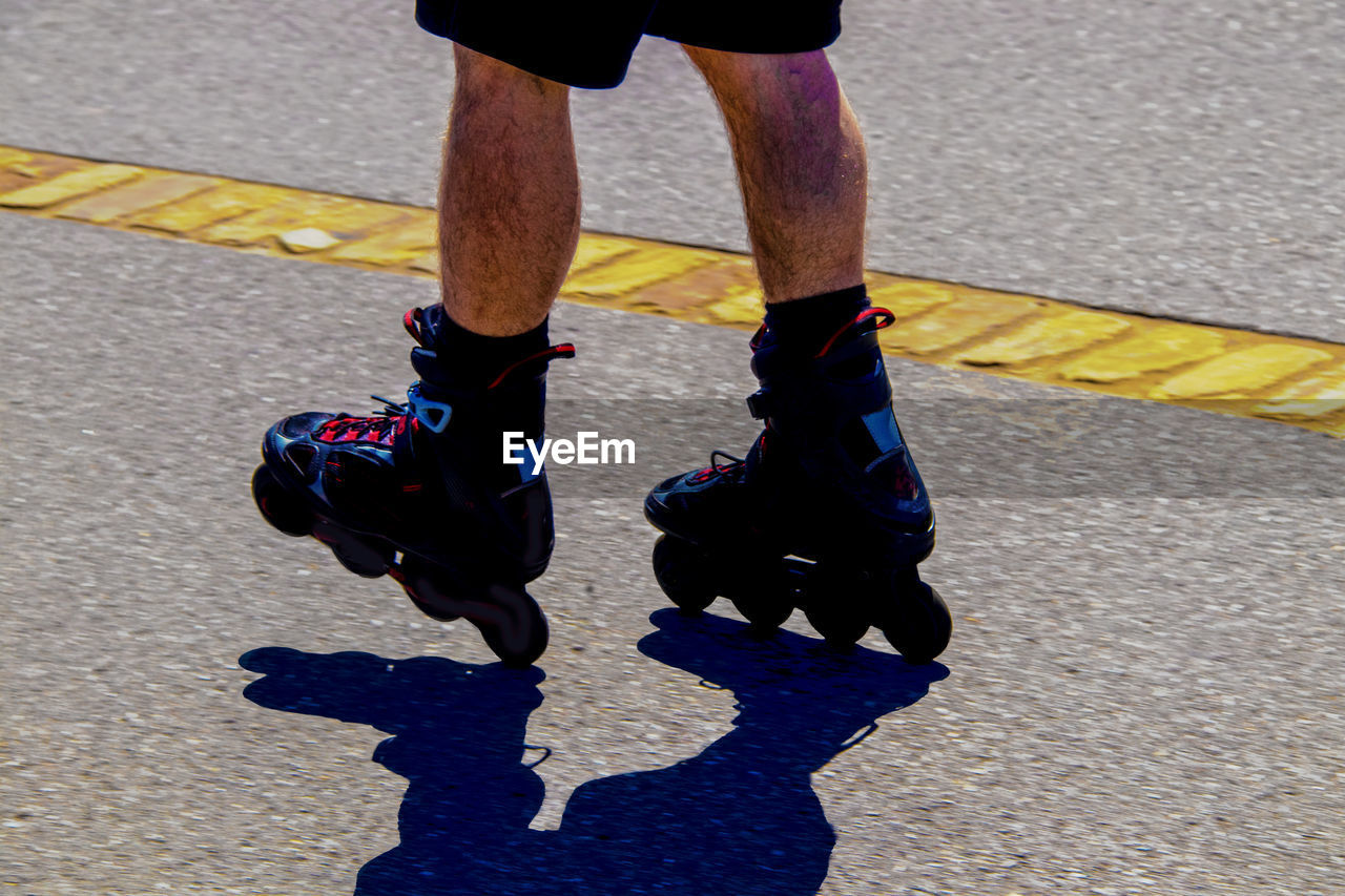 Low section of man with shadow on street