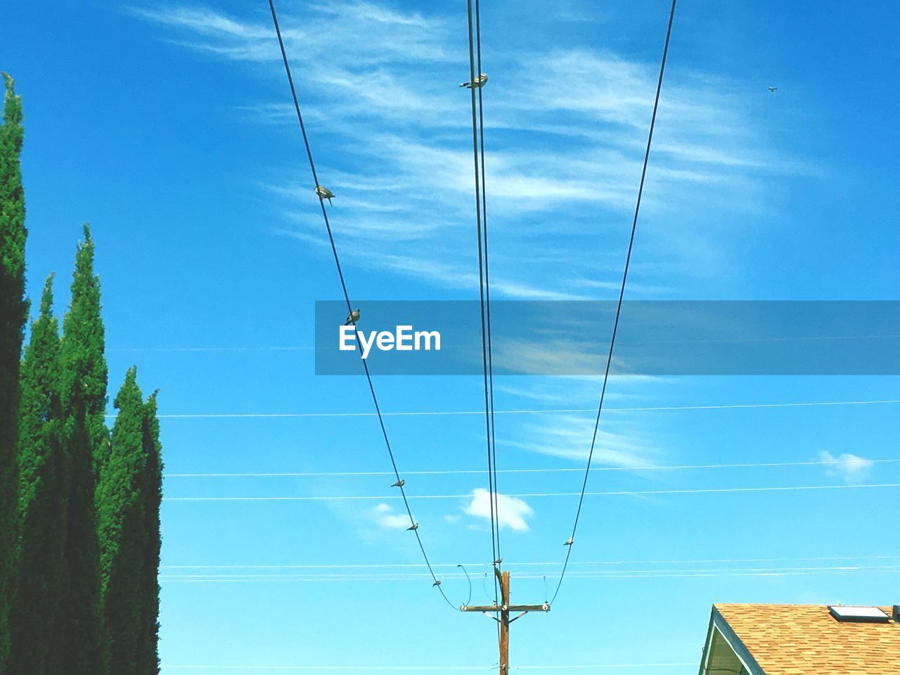 Low angle view of electricity pylon against blue sky