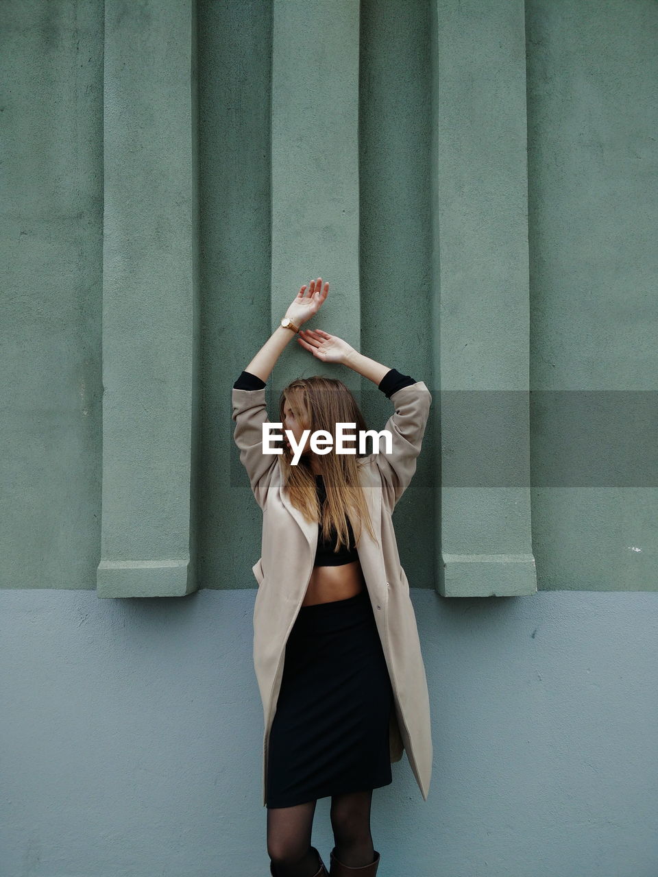 Fashionable woman looking away while standing against wall