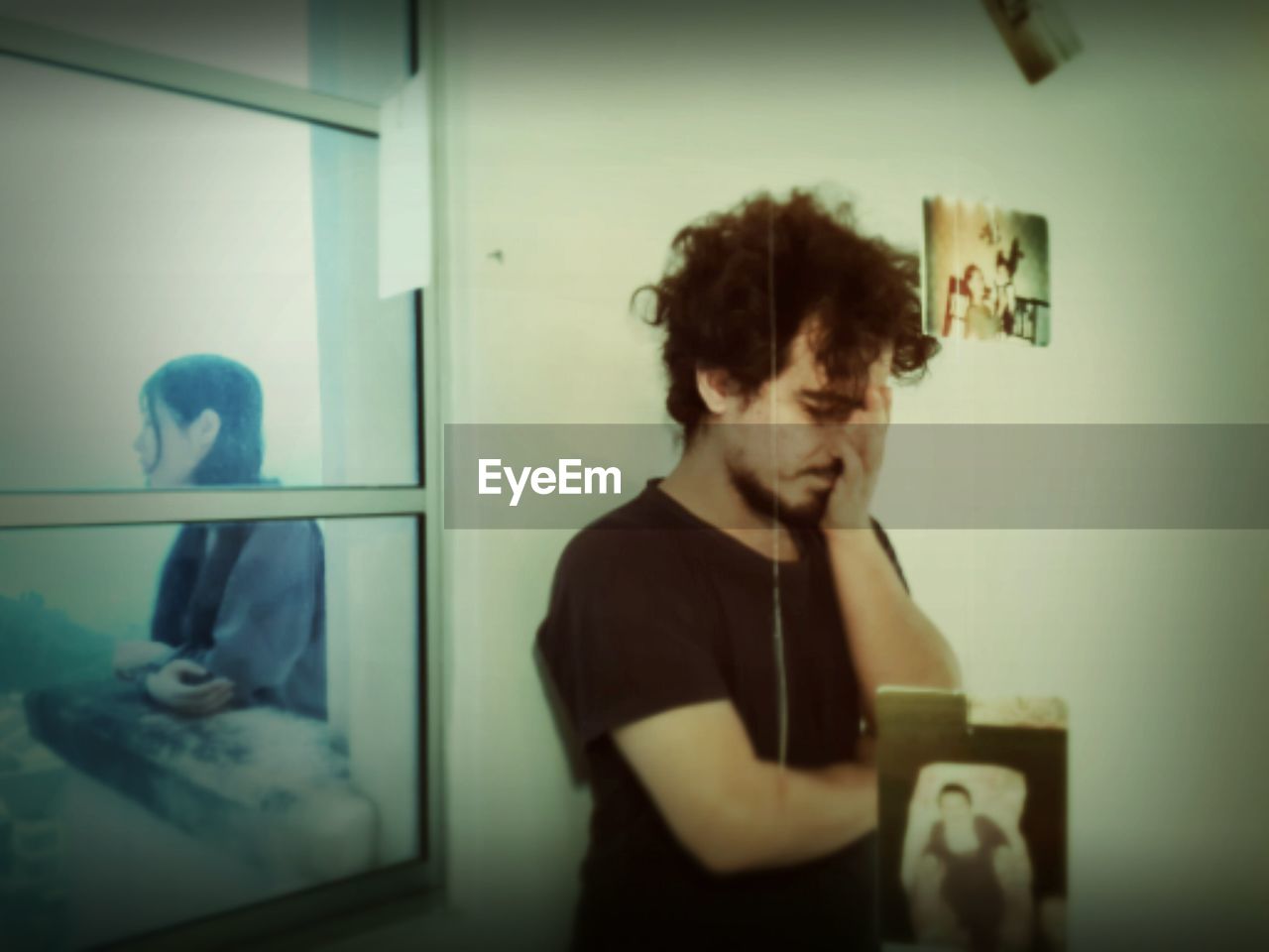 Sad woman seen through window with man standing in foreground