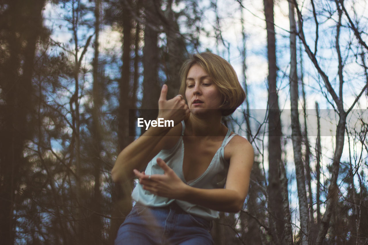 Low angle view of young woman dancing in forest