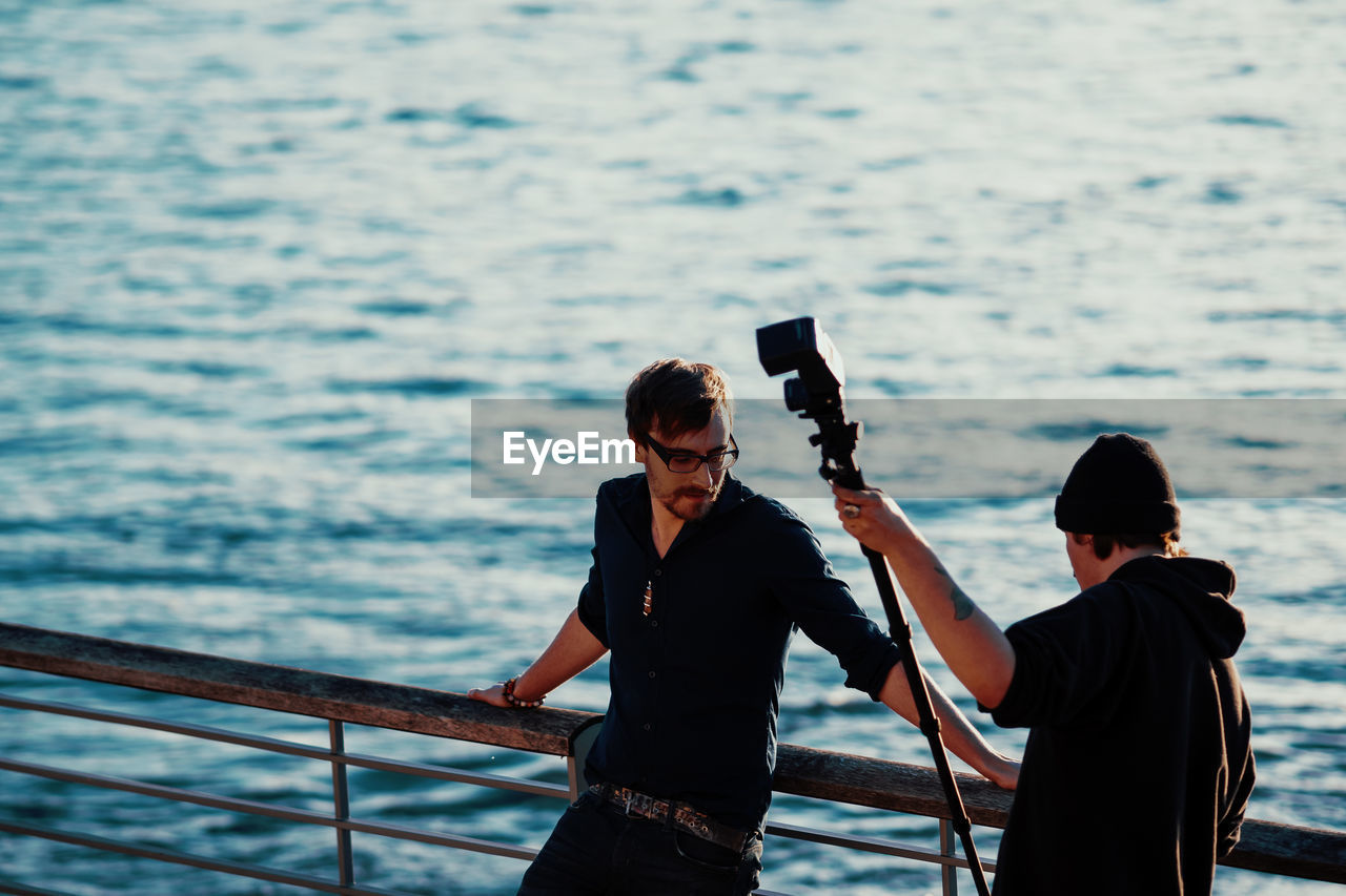 FULL LENGTH OF MAN PHOTOGRAPHING ON RAILING