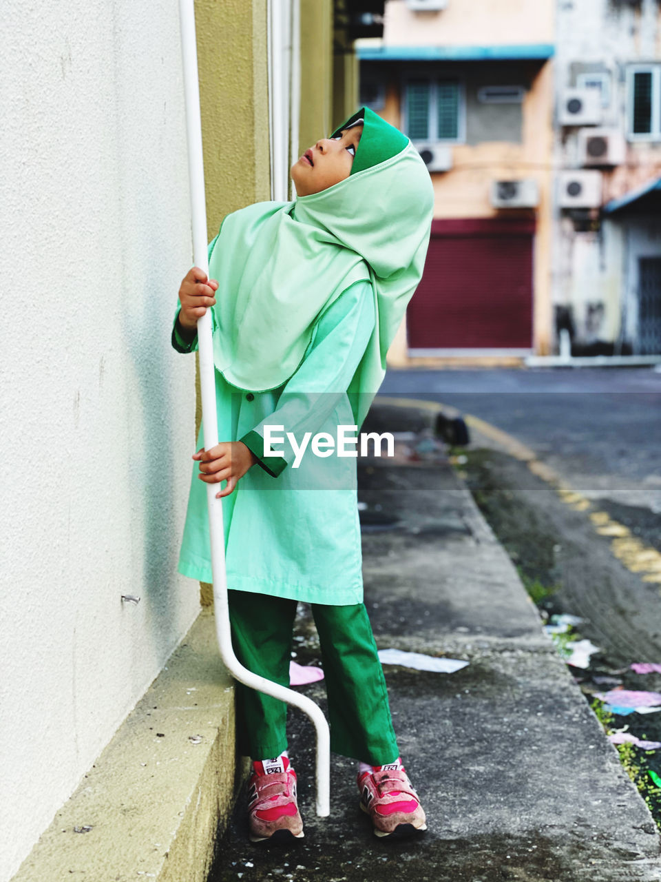 SIDE VIEW OF MAN HOLDING UMBRELLA AGAINST WALL