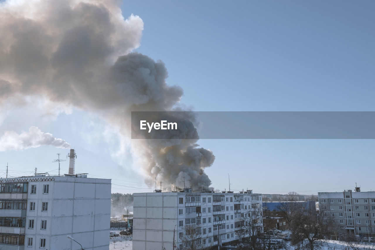 SMOKE EMITTING FROM BUILDING AGAINST SKY