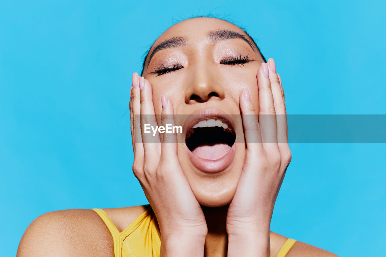 low angle view of young woman with eyes closed against blue background