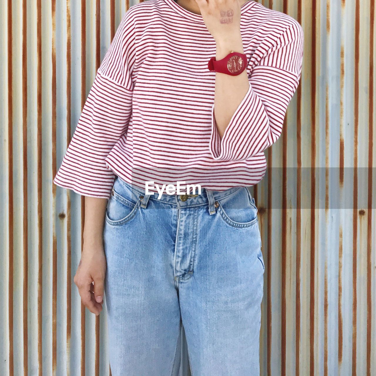 Midsection of woman standing against patterned wall