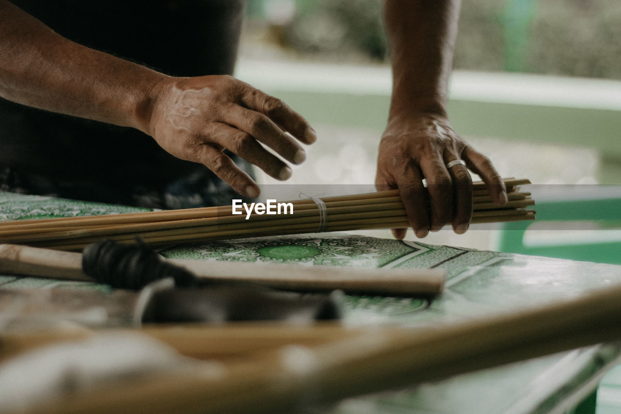 MIDSECTION OF MAN WORKING ON WOODEN FLOOR