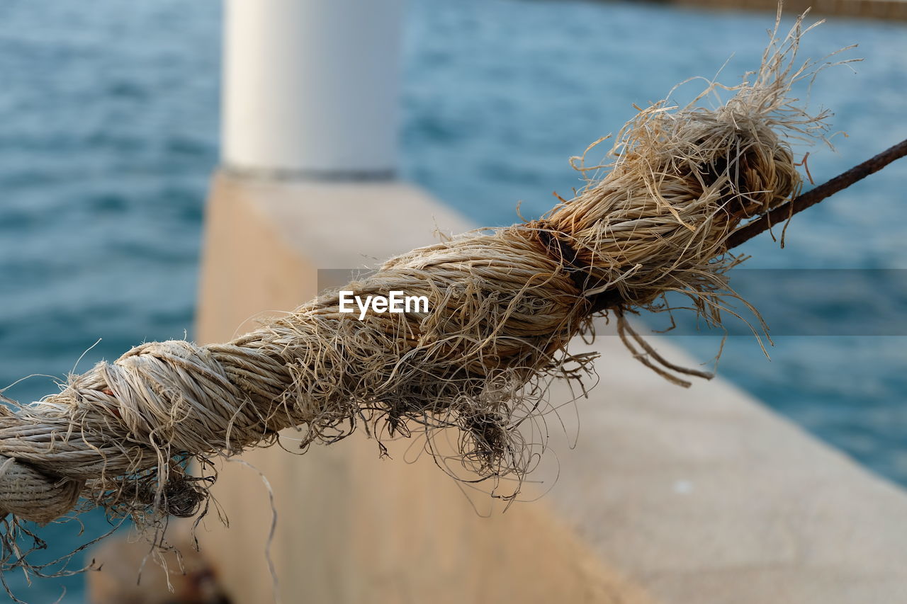 CLOSE-UP OF ROPE TIED TO FISHING NET AT SEA