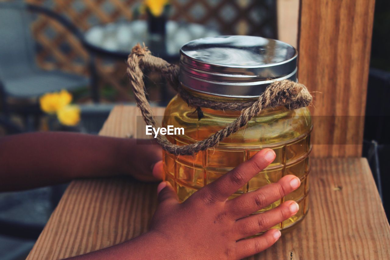 Close-up of hand holding jar on table