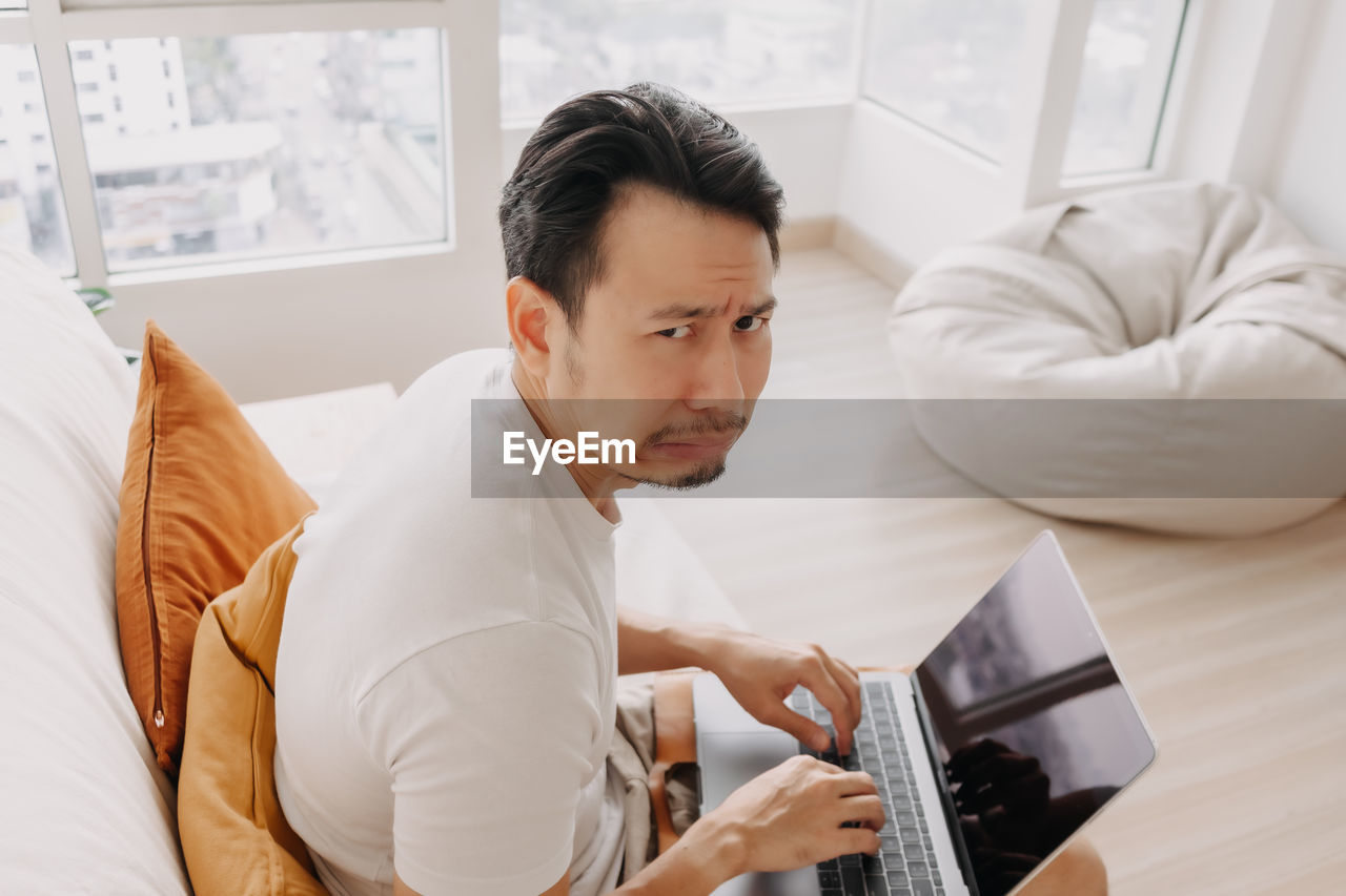 Frustrated man with laptop at home