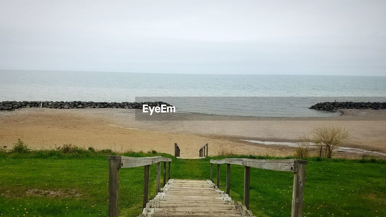 WOODEN POSTS ON BEACH AGAINST SKY