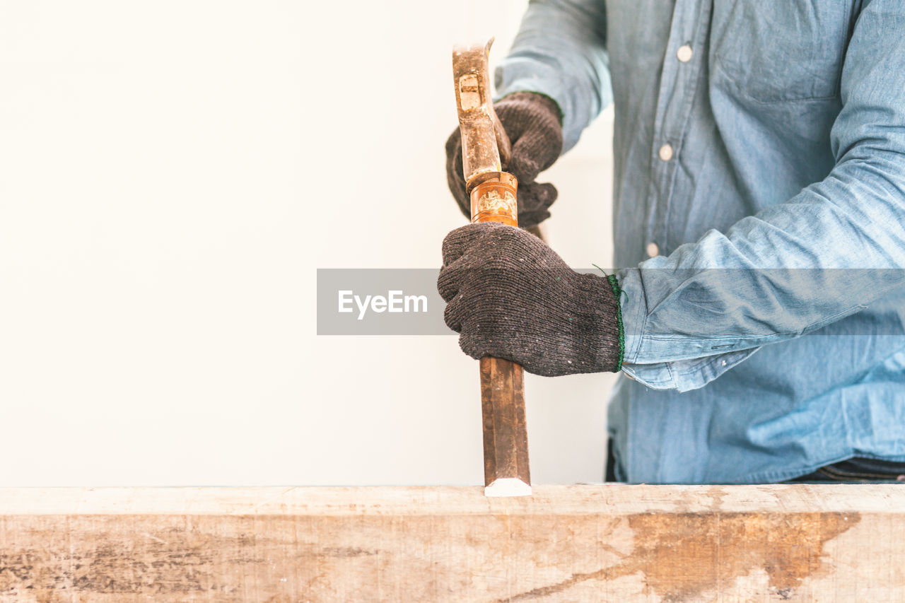 Midsection of carpenter working on wood at workshop