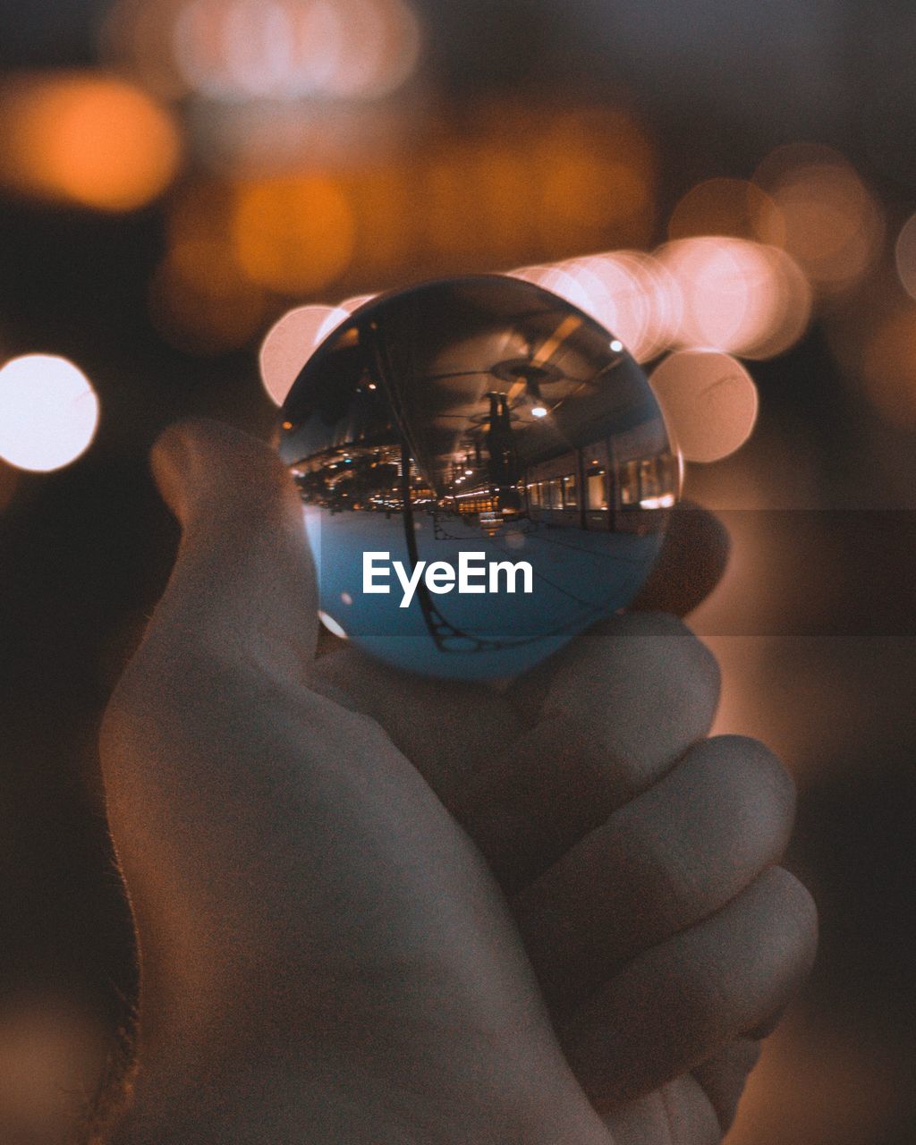 Cropped hand holding crystal ball at night