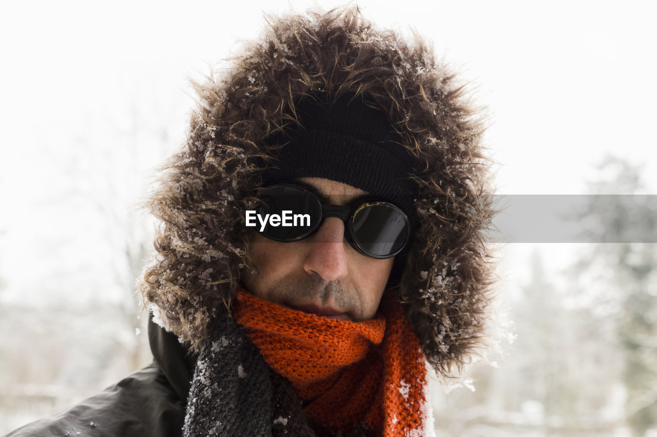 Portrait of man wearing fur coat standing against sky during winter