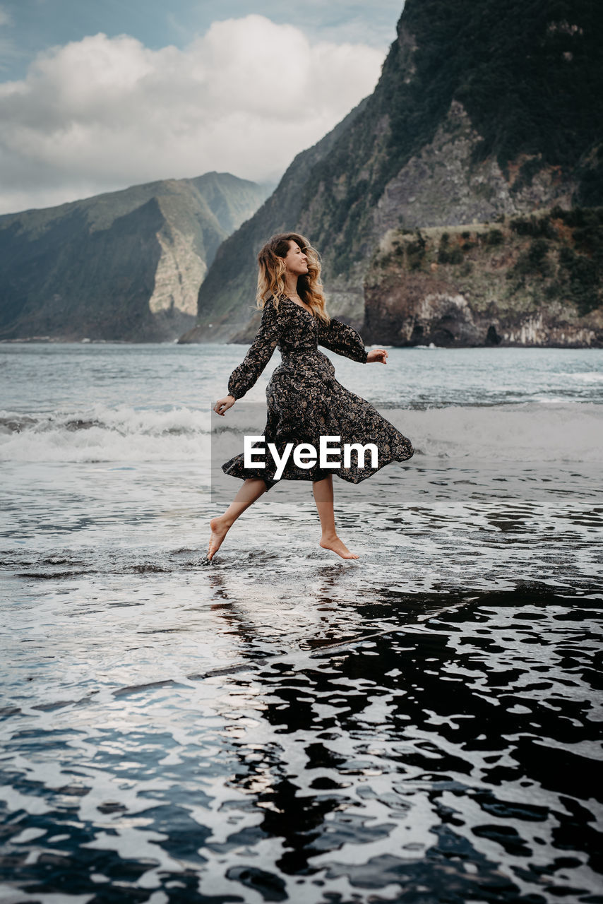 Full length of woman walking in water at beach