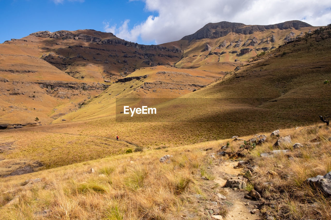 Scenic view of hiker trekking in the drakensberg mountains against sky 