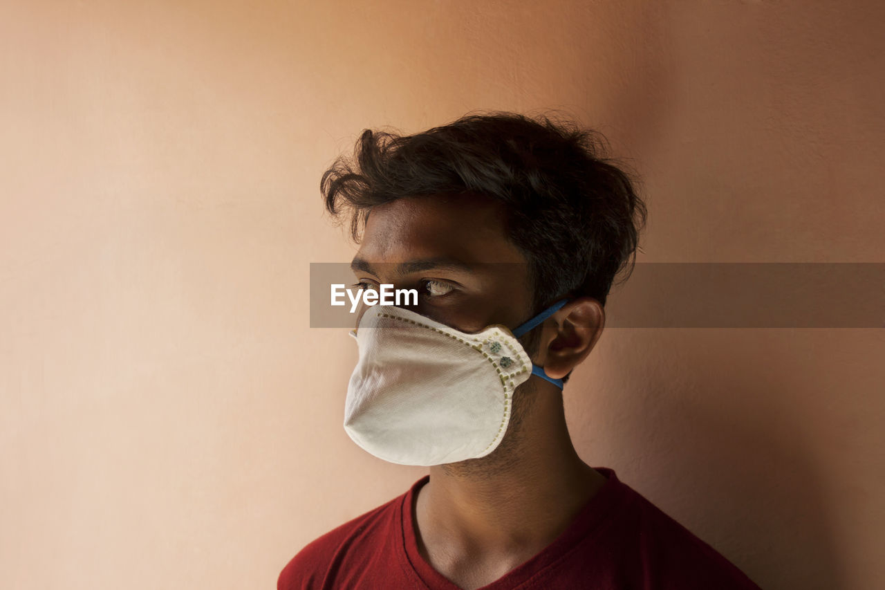 Young man with mask against wall