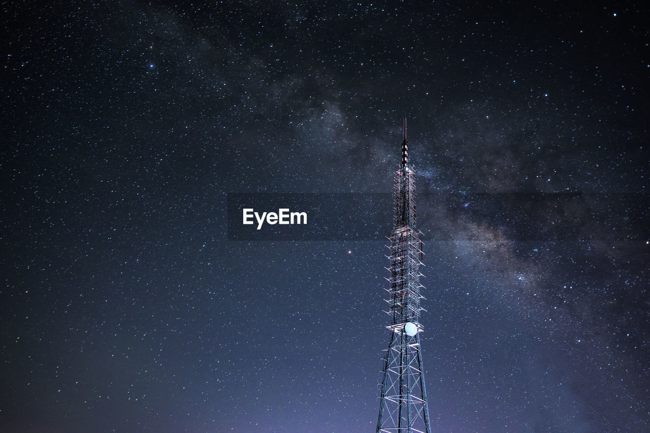 Low angle view of communications tower against galaxy