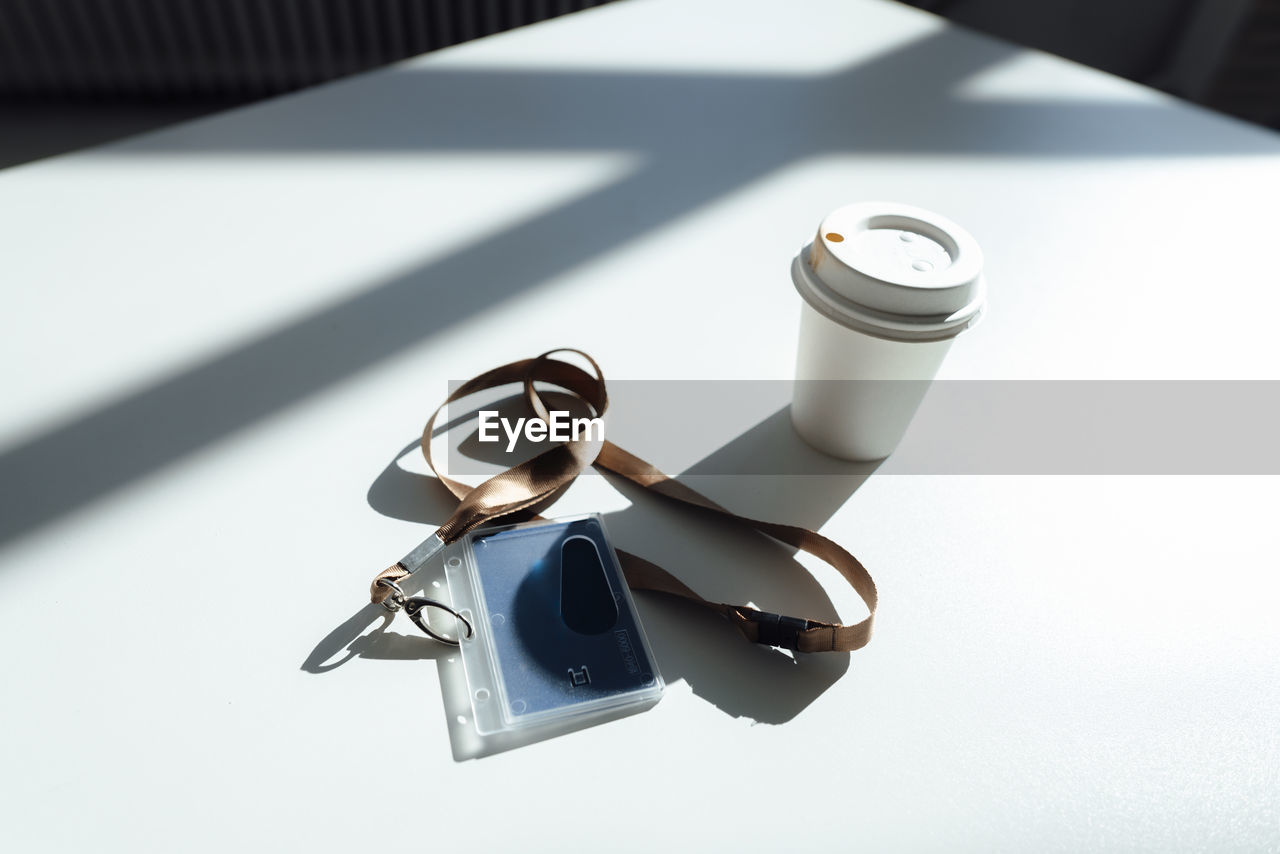 Id card and disposable cup on white desk in office