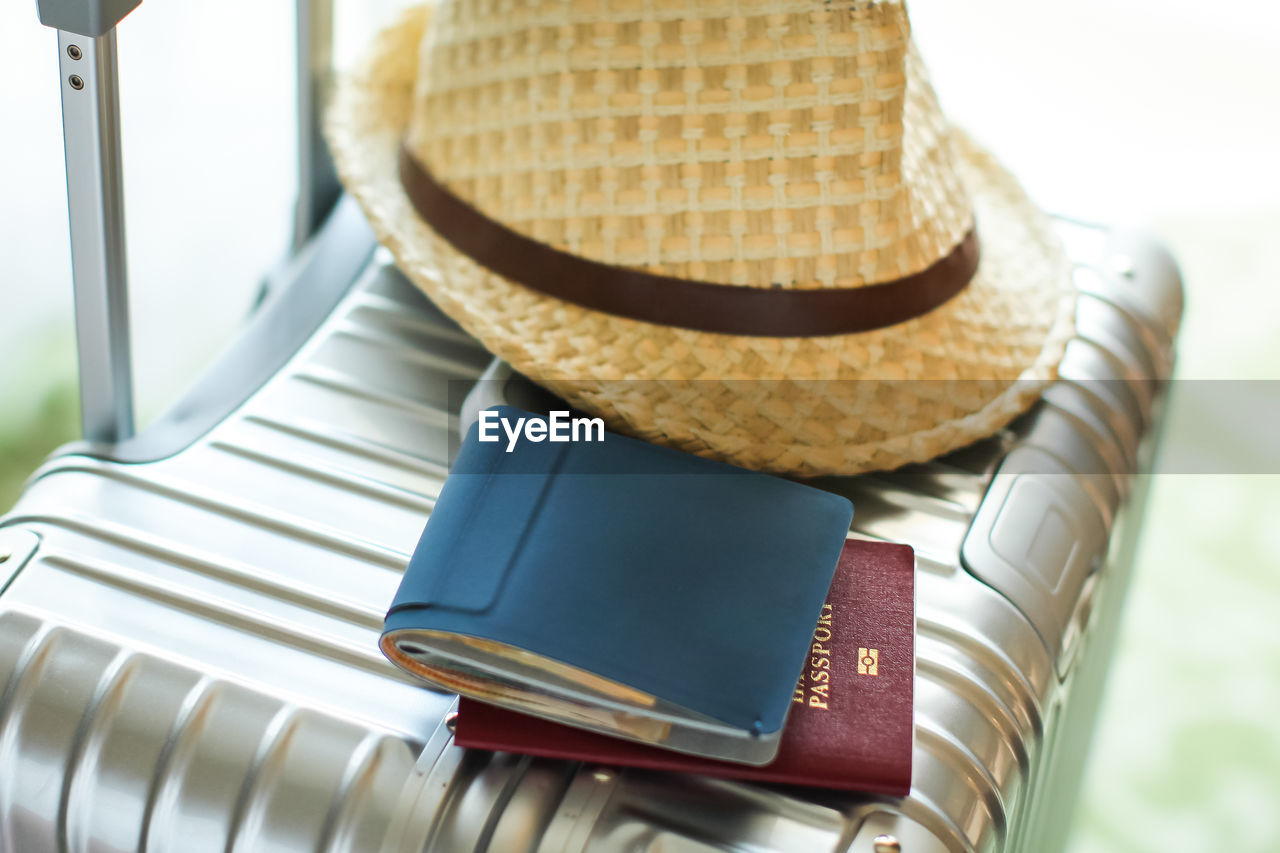 Close-up of hat and wallet with passport on suitcase
