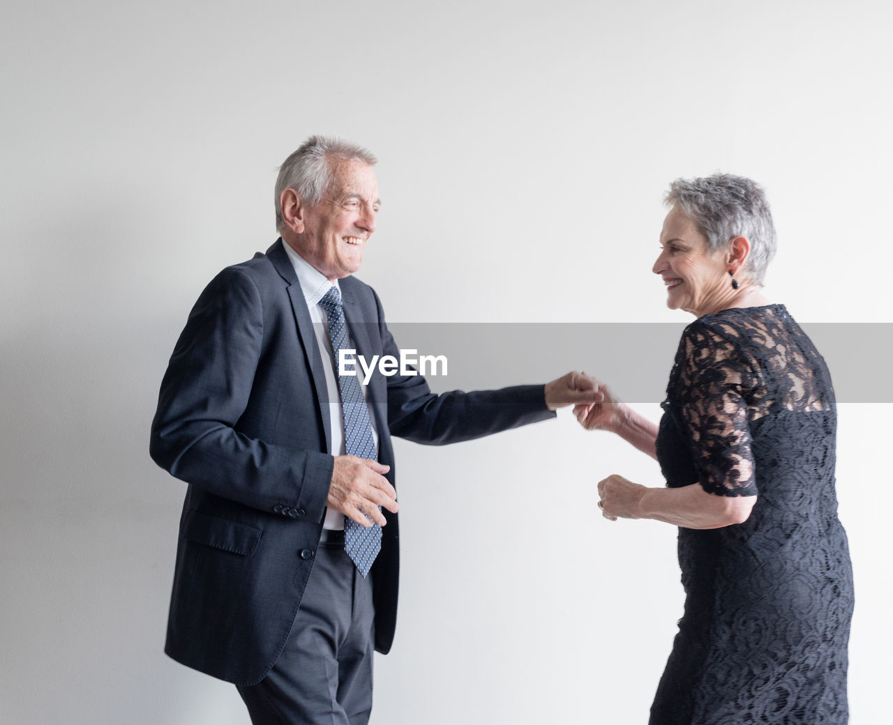 Senior couple dancing against white background