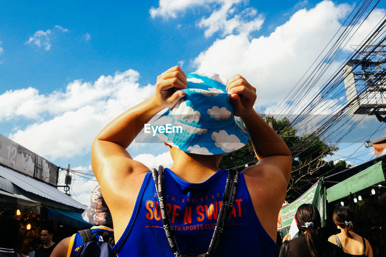 LOW ANGLE PORTRAIT OF MAN WEARING MASK AGAINST SKY