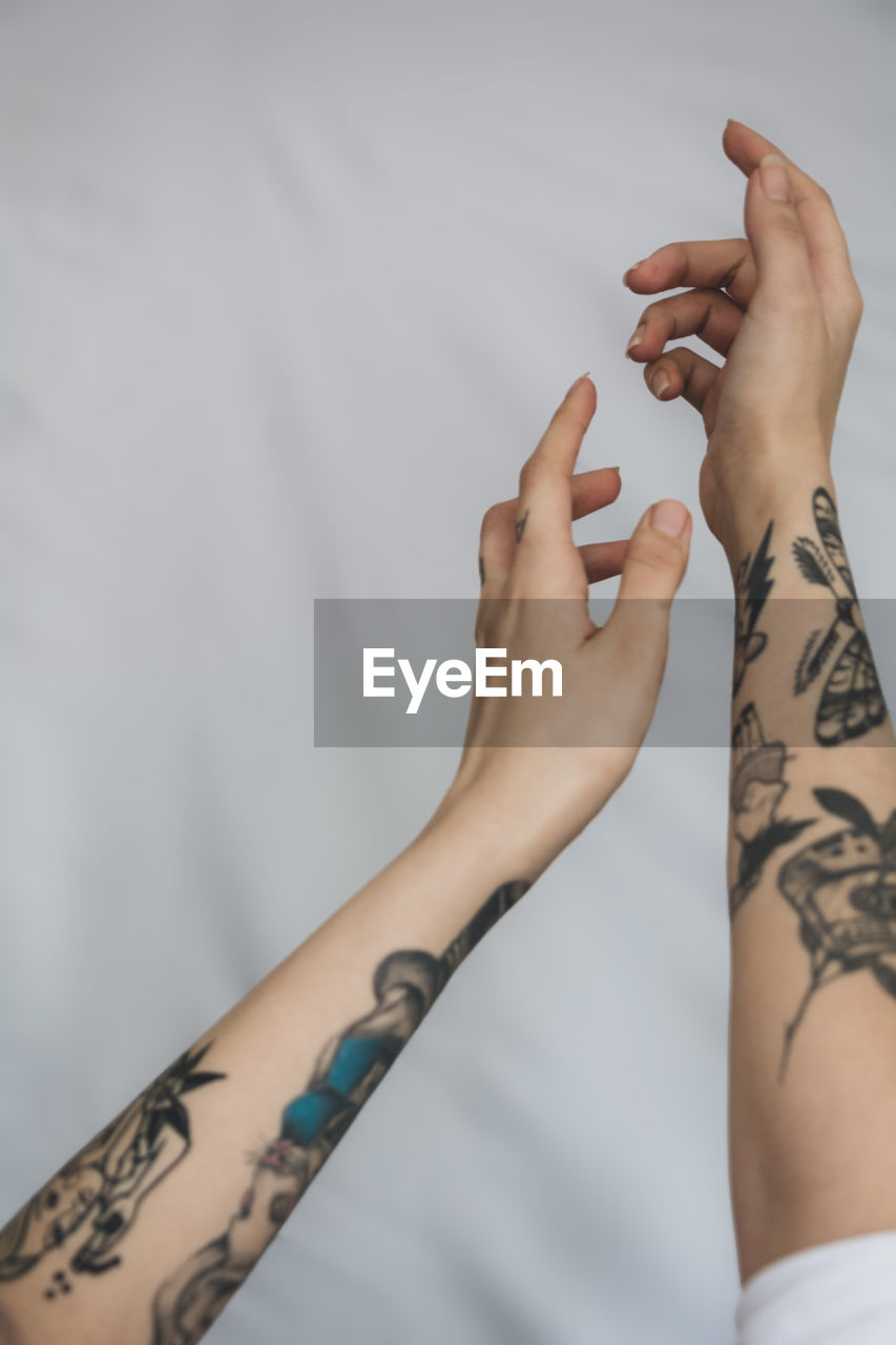 Close-up of woman's hands with tattoo against gray background