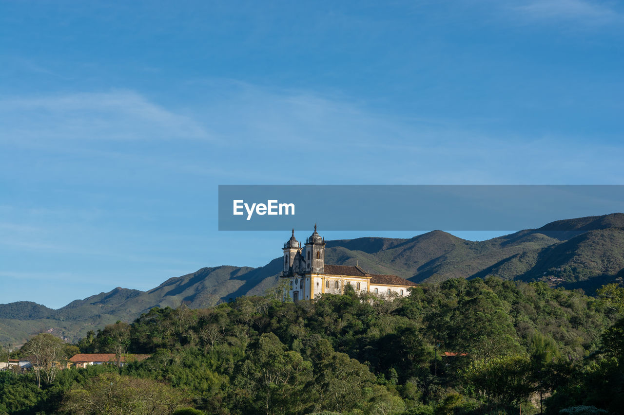 Scenic view of building and mountains against blue sky