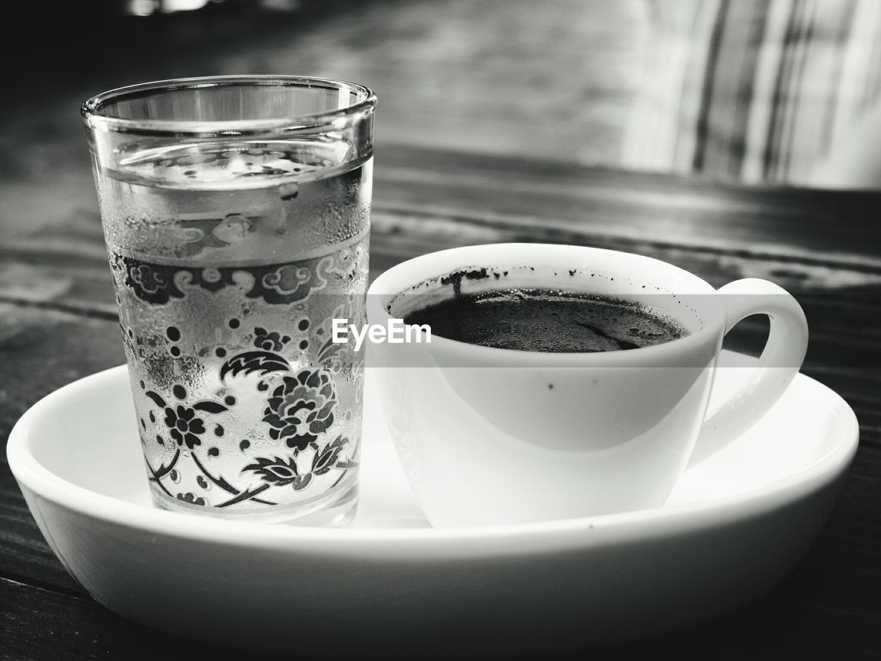 CLOSE-UP OF COFFEE CUP ON GLASS TABLE