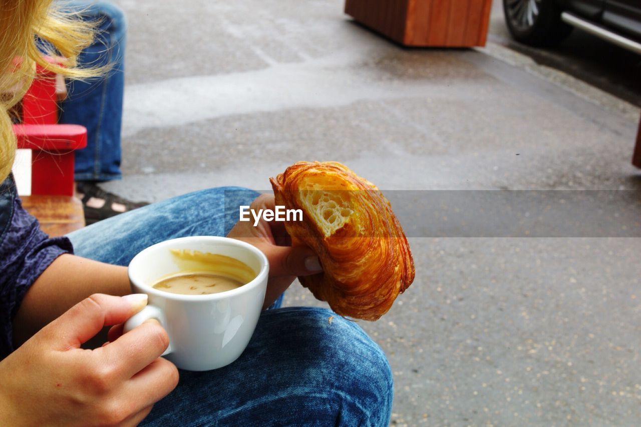 MIDSECTION OF WOMAN HOLDING COFFEE CUP