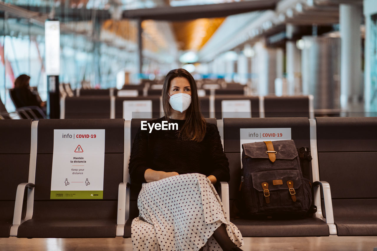 Woman wearing mask sitting at airport