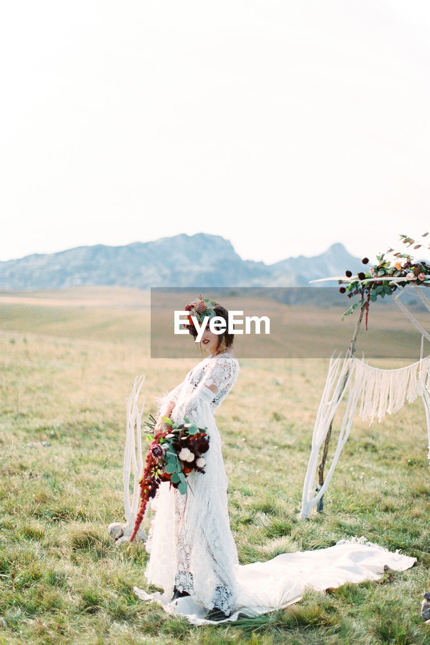 Full length of bride standing on field against sky