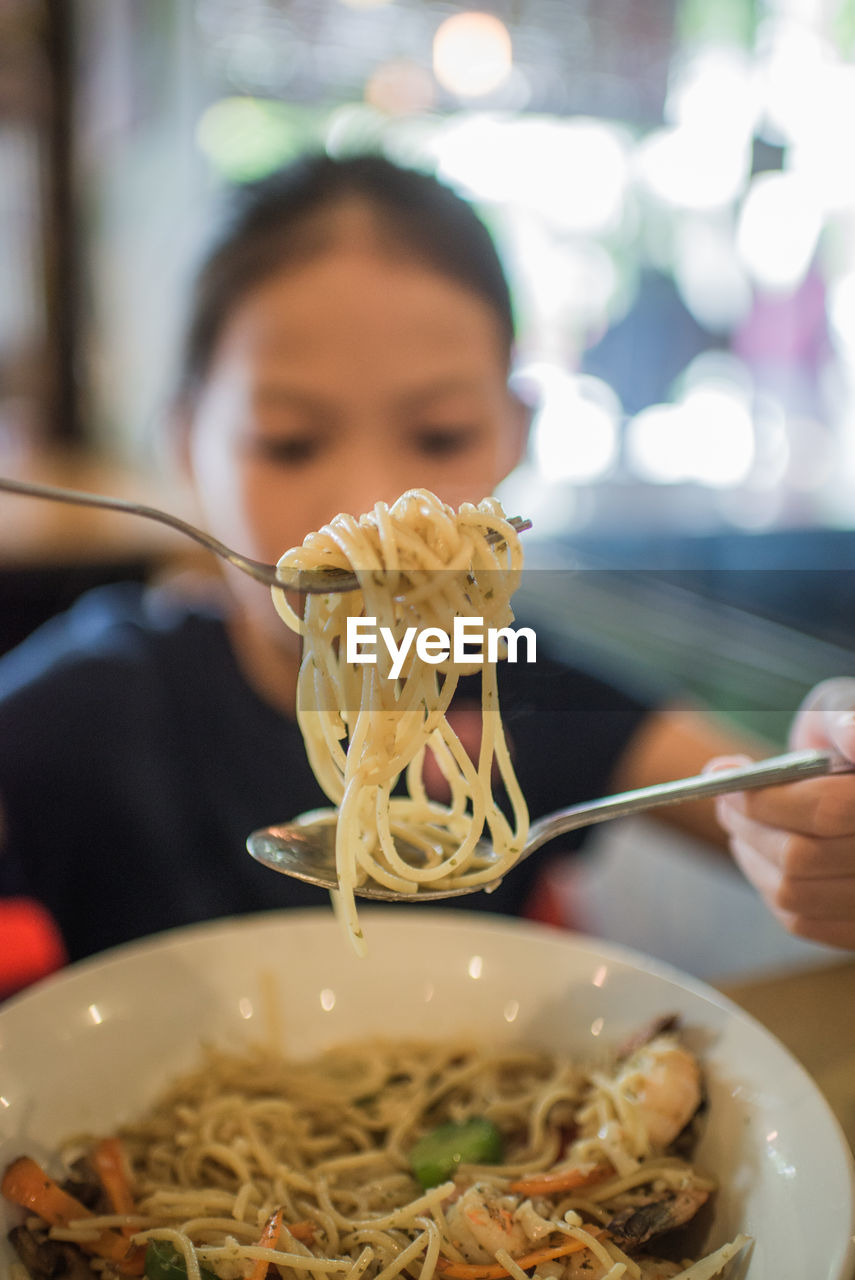 Young woman eating pasta at restaurant