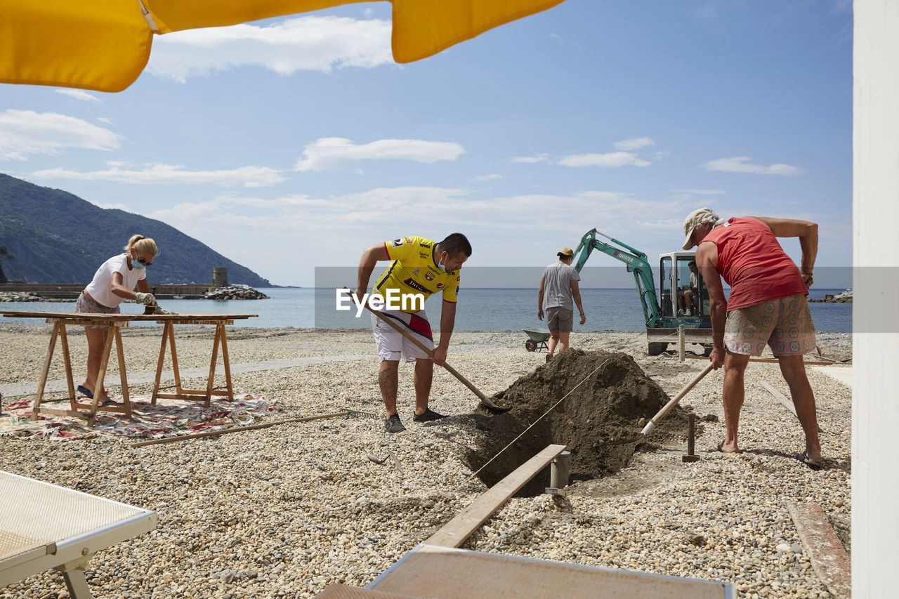 PEOPLE ON BEACH AGAINST SKY