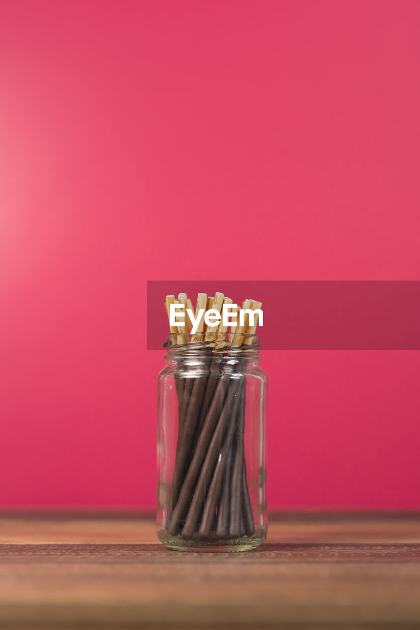 Chocolate dipped stick in a mason jar on a wooden table. concept of sweet food and confectionery