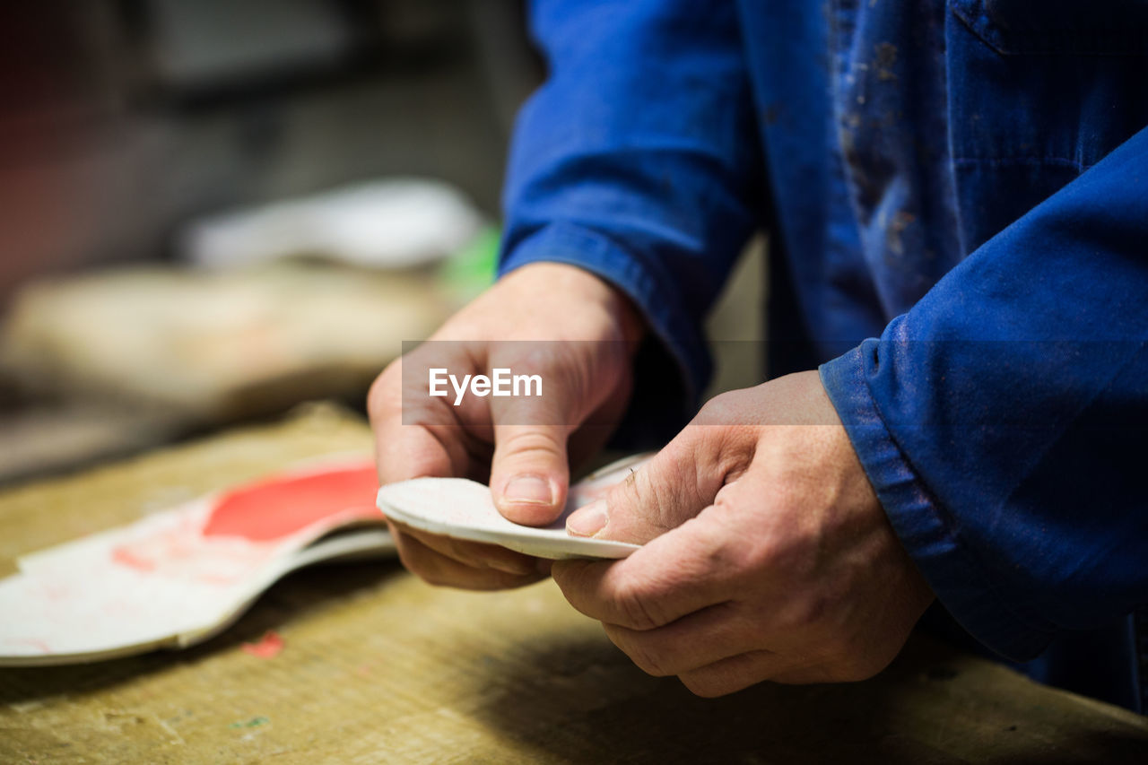 Midsection of man making footwear