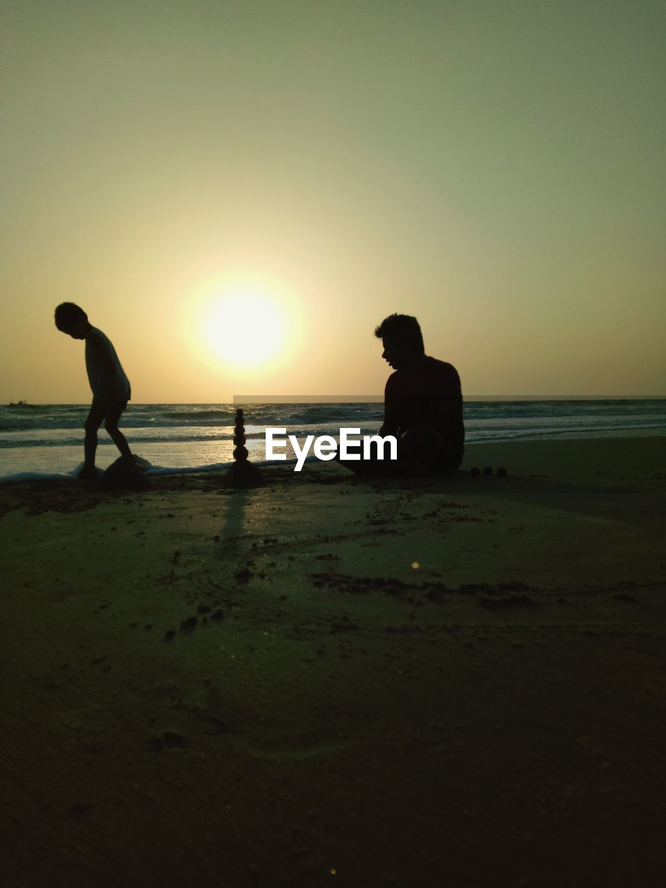 Silhouette of father and son at beach during sunset