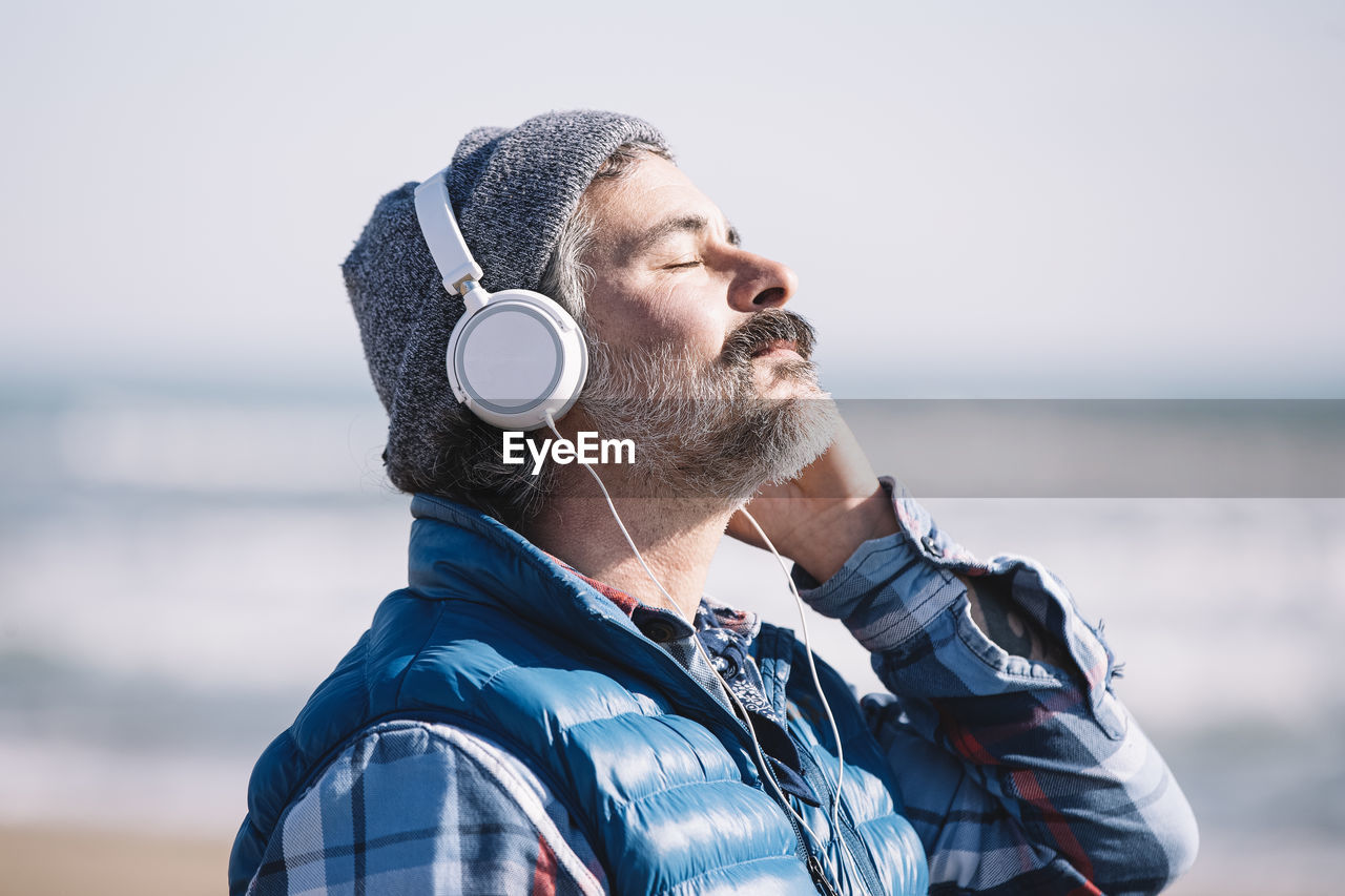 Caucasian man meditating on the beach with headphones in winter person