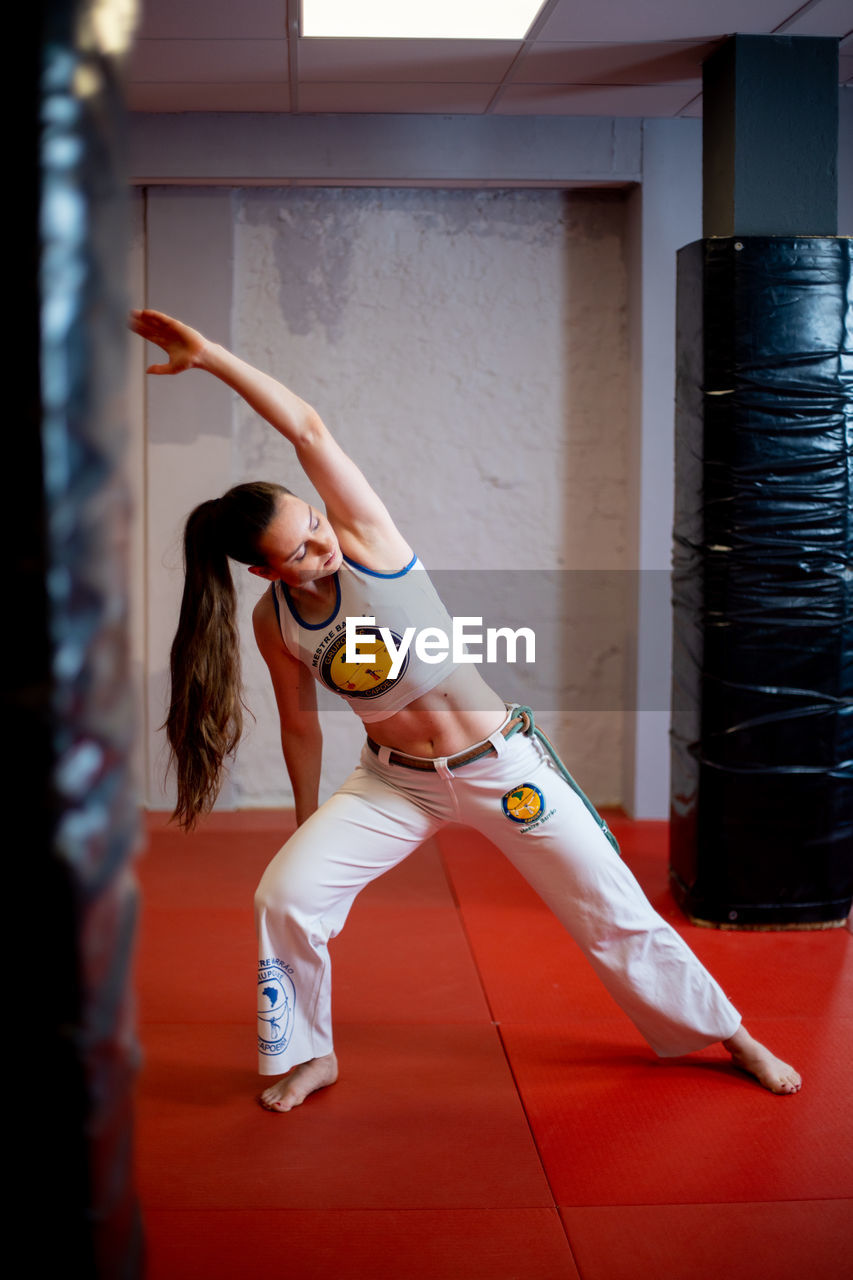 FULL LENGTH OF WOMAN WITH ARMS RAISED IN ROOM