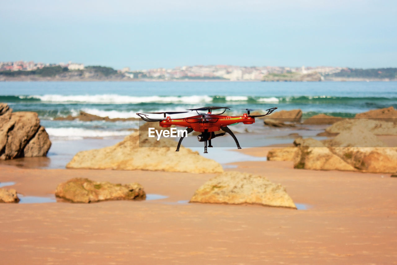 Orange flying drone on the beach