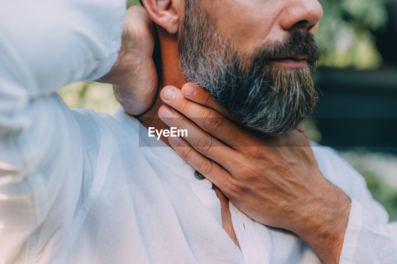 Reiki practitioner healing his throat chakra with his eyes closed. alternative therapy concept.