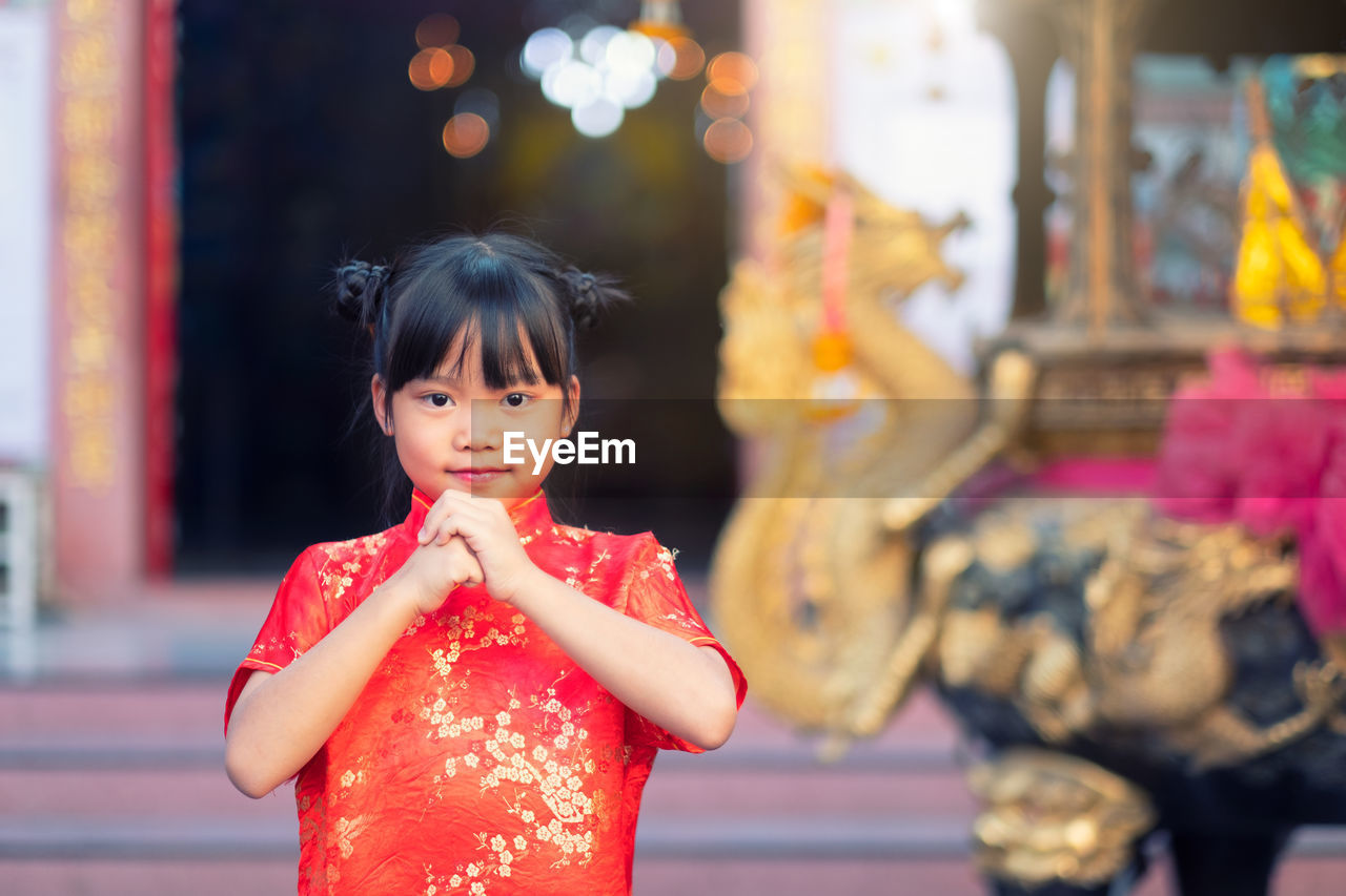 Portrait of girl greeting chinese new year while standing outdoors